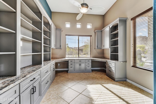 unfurnished office featuring ceiling fan, light tile patterned floors, and built in desk