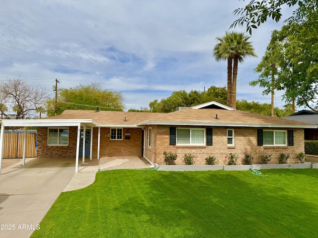 rear view of property featuring driveway, an attached carport, a lawn, and brick siding