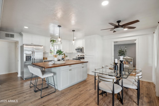 kitchen featuring white cabinets, butcher block counters, visible vents, and stainless steel appliances