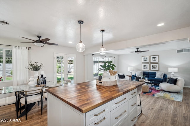 kitchen featuring butcher block counters, visible vents, open floor plan, and wood finished floors