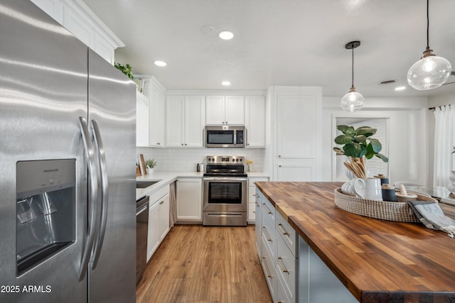 kitchen with stainless steel appliances, butcher block countertops, backsplash, and white cabinets