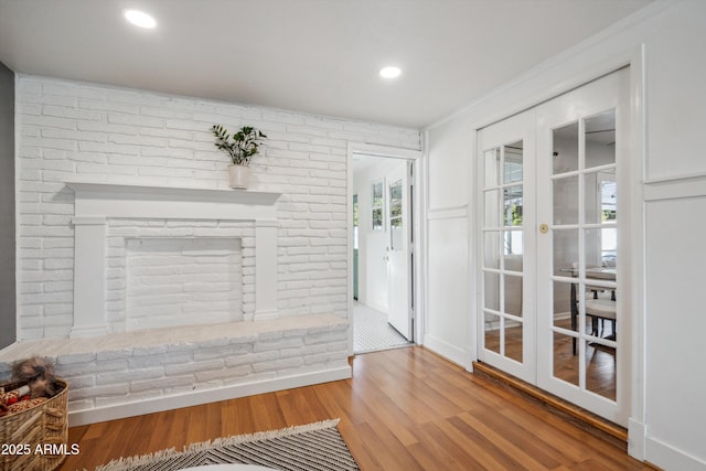 doorway with brick wall, a fireplace, wood finished floors, and recessed lighting