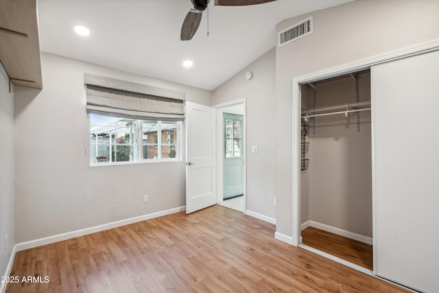 unfurnished bedroom featuring wood finished floors, visible vents, baseboards, vaulted ceiling, and a closet