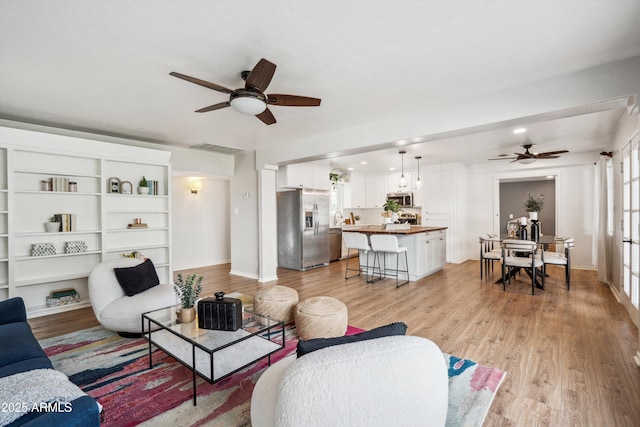 living room with light wood-style flooring, baseboards, and a ceiling fan