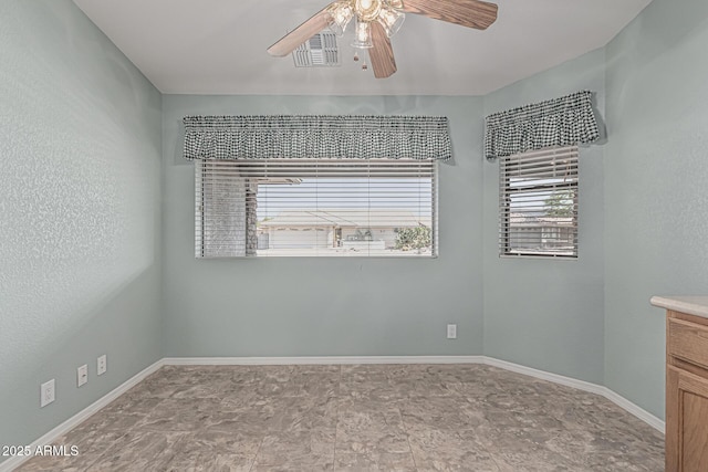 spare room with baseboards, ceiling fan, and a healthy amount of sunlight