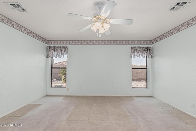 carpeted spare room featuring baseboards, a ceiling fan, and visible vents
