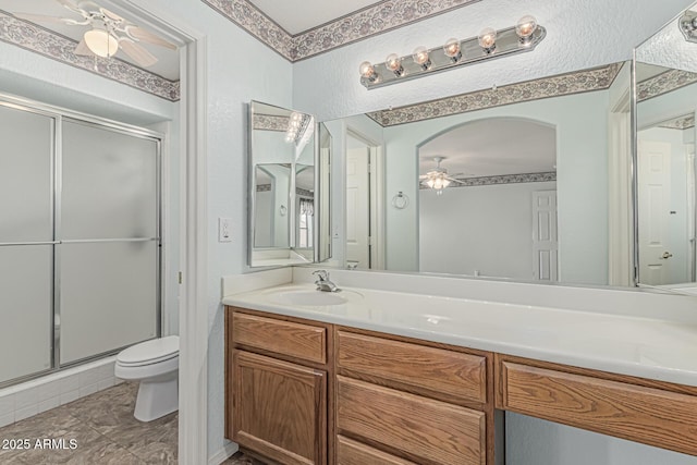 full bathroom featuring vanity, ceiling fan, toilet, and a shower stall