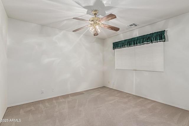 carpeted spare room with visible vents, baseboards, and ceiling fan