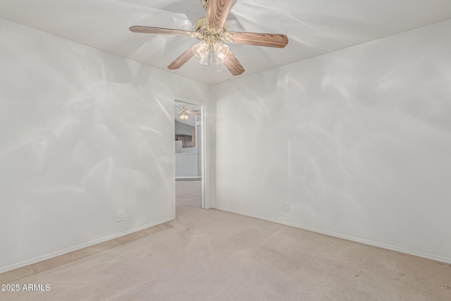 carpeted spare room featuring baseboards and ceiling fan