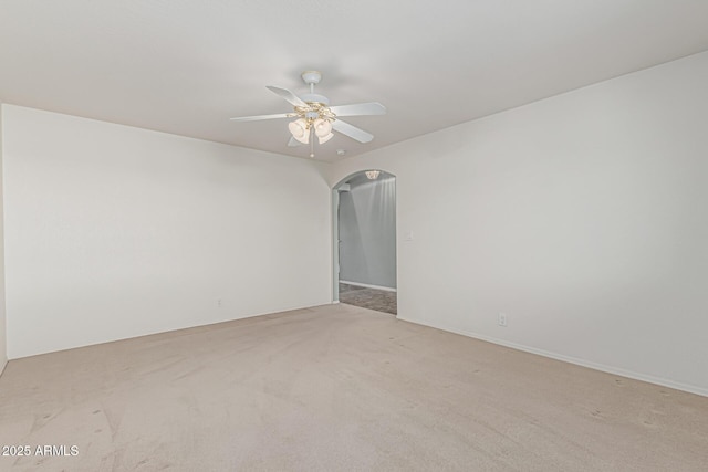 unfurnished room featuring arched walkways, a ceiling fan, and light colored carpet