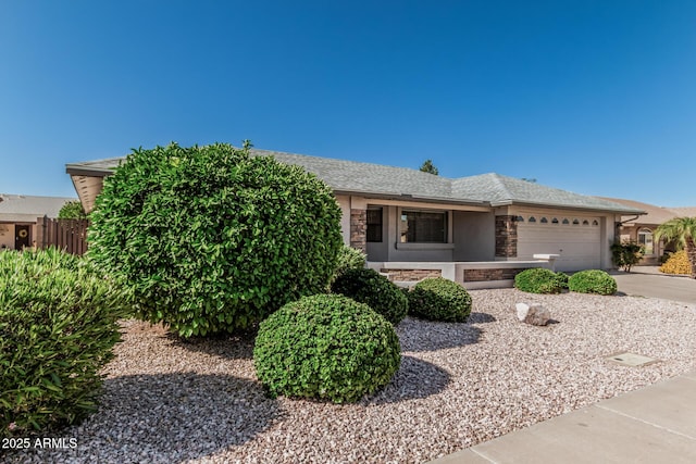 view of front of house with fence, stone siding, a garage, stucco siding, and driveway