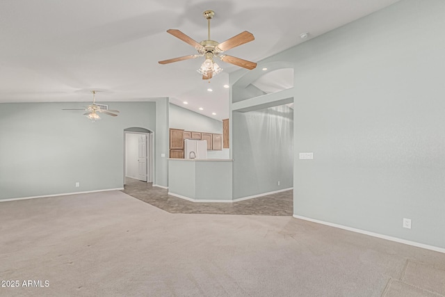 unfurnished living room with light colored carpet, a ceiling fan, arched walkways, and vaulted ceiling