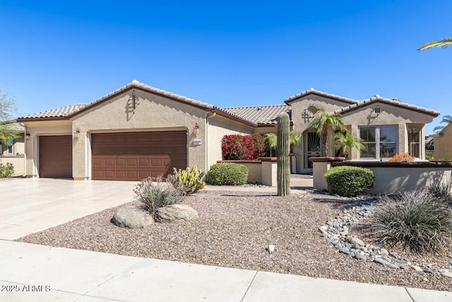 mediterranean / spanish house with an attached garage, driveway, a tile roof, and stucco siding