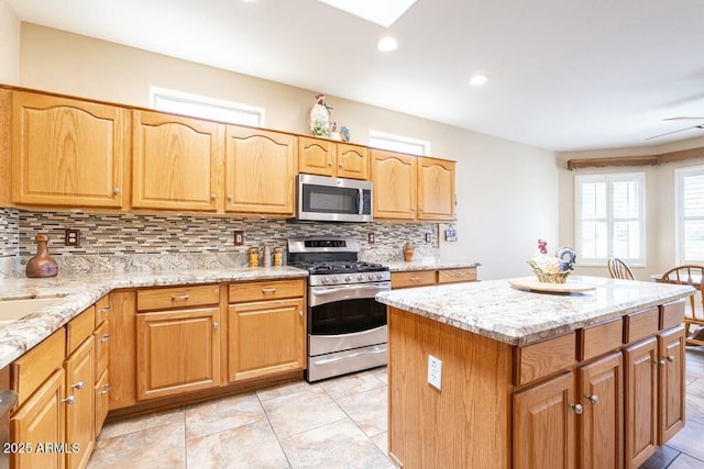 kitchen featuring stainless steel appliances, light stone counters, a center island, and tasteful backsplash