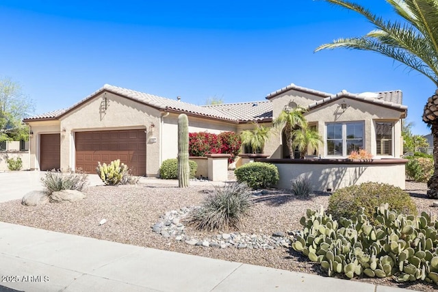 mediterranean / spanish-style house featuring driveway, an attached garage, a tile roof, and stucco siding