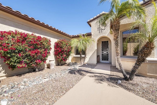 doorway to property with a tiled roof and stucco siding