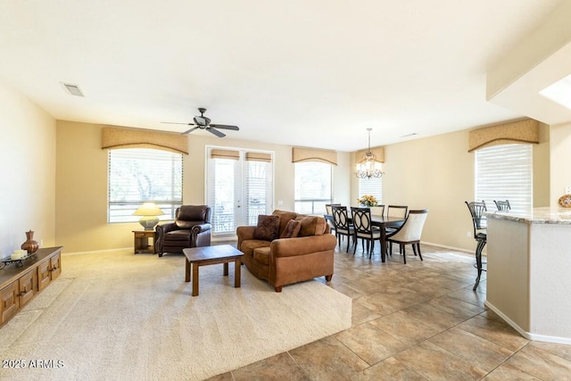 living area with visible vents, baseboards, and ceiling fan with notable chandelier