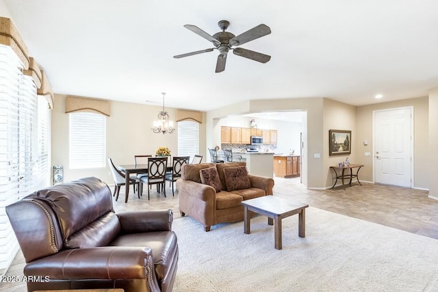 living area with baseboards and ceiling fan with notable chandelier