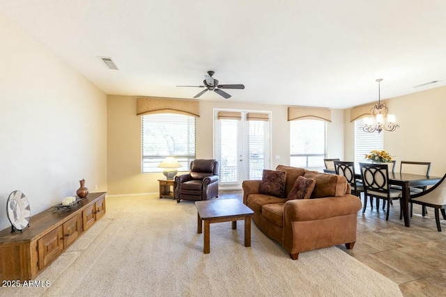 living area with ceiling fan with notable chandelier, light carpet, and visible vents