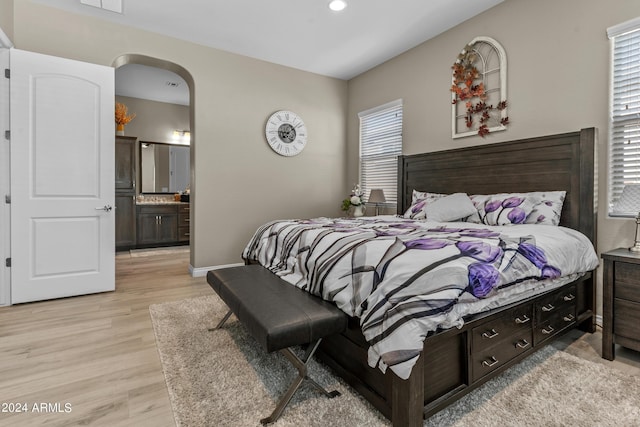 bedroom with connected bathroom and light hardwood / wood-style flooring