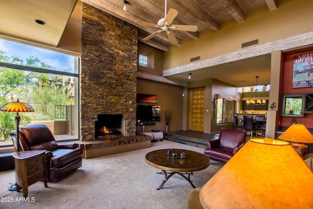 living area with a high ceiling, beam ceiling, a fireplace, wooden ceiling, and visible vents