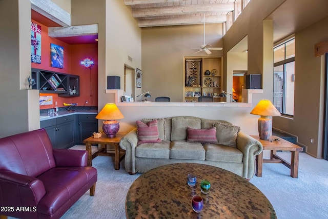 carpeted living area featuring visible vents, beamed ceiling, a high ceiling, wooden ceiling, and a ceiling fan