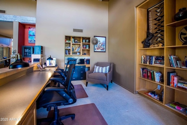 office space with a towering ceiling, carpet, and visible vents