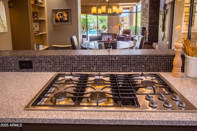 interior details featuring stainless steel gas stovetop, decorative backsplash, and an inviting chandelier