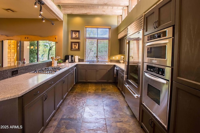 kitchen with appliances with stainless steel finishes, light countertops, a peninsula, visible vents, and stone tile flooring