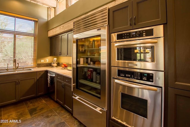 kitchen featuring a sink, stone finish flooring, appliances with stainless steel finishes, and light countertops