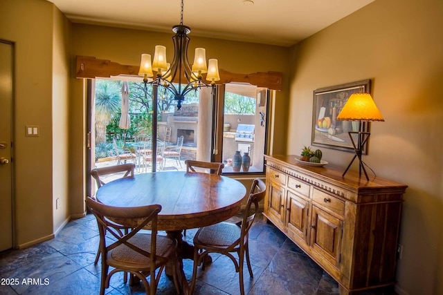 dining area featuring baseboards, stone tile flooring, and a notable chandelier