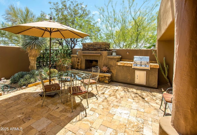 view of patio featuring exterior kitchen, outdoor dining space, area for grilling, and an outdoor stone fireplace