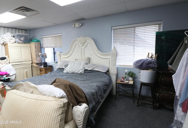 bedroom featuring dark carpet, a drop ceiling, and visible vents