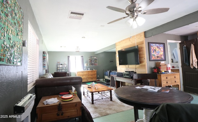 living room featuring wood walls, visible vents, and a ceiling fan