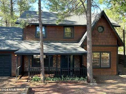 view of front of house featuring a porch, an attached garage, and stone siding