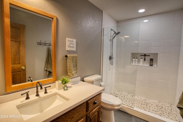 bathroom featuring recessed lighting, a tile shower, a textured wall, toilet, and vanity