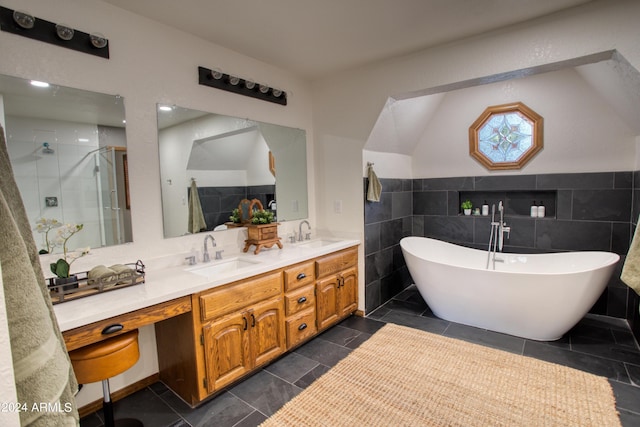 bathroom with a shower stall, tile walls, double vanity, and a sink