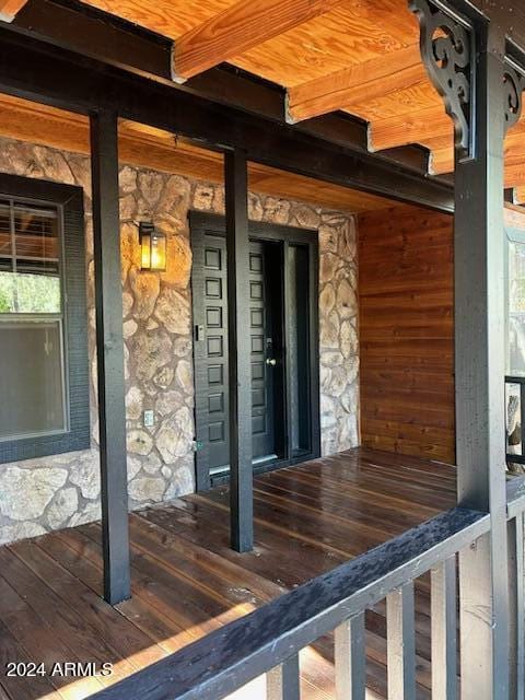 view of exterior entry with stone siding and a porch