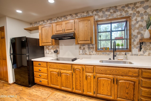 kitchen featuring black appliances, under cabinet range hood, a sink, and light countertops