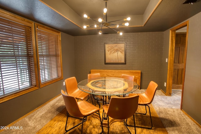 carpeted dining area featuring a chandelier, baseboards, and a tray ceiling