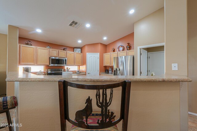 kitchen featuring stainless steel appliances, recessed lighting, visible vents, light brown cabinets, and vaulted ceiling