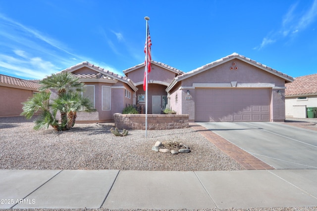 view of front of home featuring concrete driveway, an attached garage, a tiled roof, and stucco siding