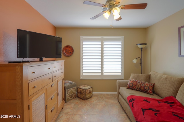 living area featuring light tile patterned flooring, ceiling fan, and baseboards