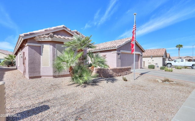 view of front of home with a garage, a tile roof, driveway, a residential view, and stucco siding