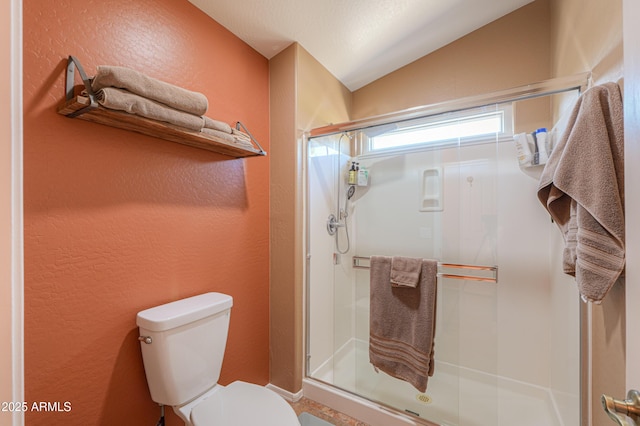 full bathroom featuring lofted ceiling, a textured wall, a shower stall, and toilet