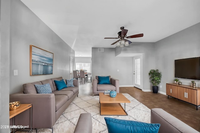 living area featuring concrete floors, baseboards, a ceiling fan, and visible vents