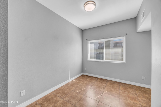 spare room featuring tile patterned flooring, visible vents, and baseboards