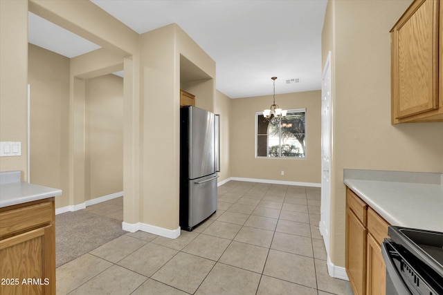 kitchen featuring pendant lighting, light tile patterned floors, stainless steel fridge, stove, and a notable chandelier