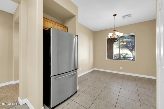 kitchen featuring light brown cabinetry, a notable chandelier, stainless steel refrigerator, and light tile patterned flooring