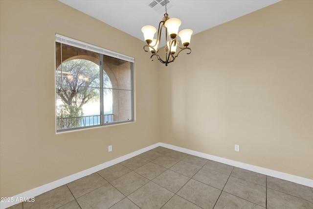 spare room with tile patterned flooring, a healthy amount of sunlight, and an inviting chandelier